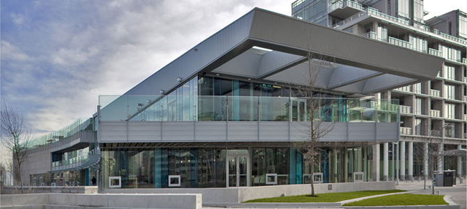 Exterior of a modern building with large windows and a covered terrace.