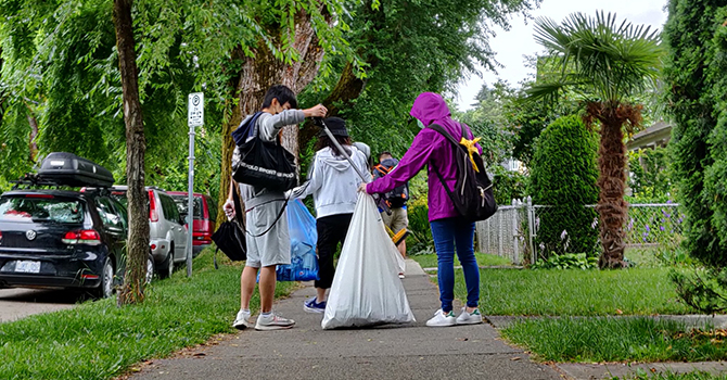 Volunteers place litter into a trash bag in a residential neighbourhood