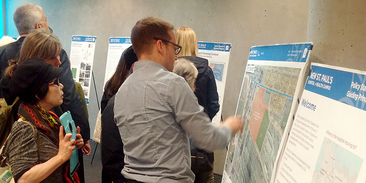 People reading and discussing information on panels at an open house People reading and discussing information on panels at an open house