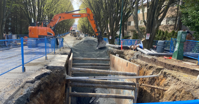 An excavator covering a hole in the road for sewer pipes.