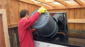 Man emptying a container into an on-site composting system