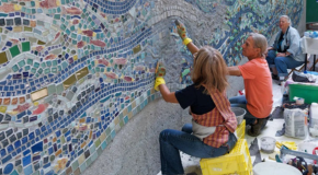 People working on a wall mosaic outdoors