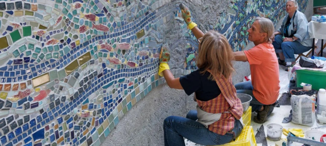 People working on a wall mosaic outdoors
