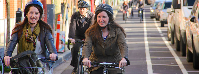 Cylists on a bike lane next to parked cars