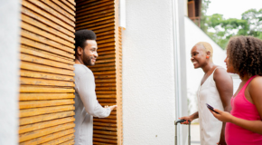 A person welcoming two other people into their house