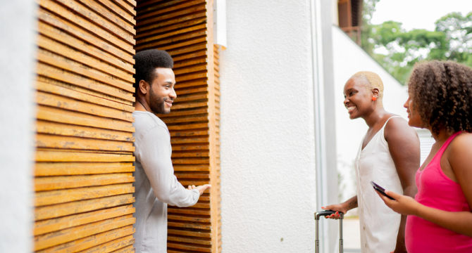 A person welcoming two other people into their house A person welcoming two other people into their house