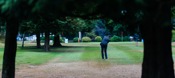 A golfer lines up their shot on a pitch and putt course.