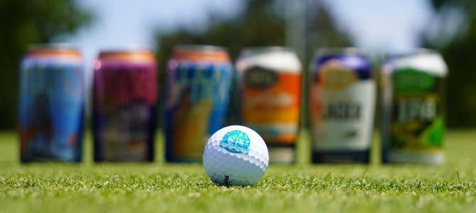 A golf ball sits in front of cans of beer 