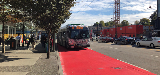 Bus driving down a lane painted red Bus driving down a lane painted red