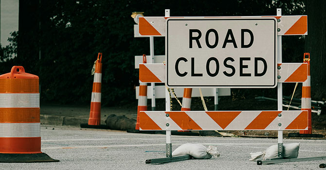 A road closed sign and orange cones around it