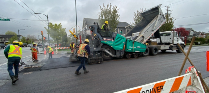 Construction workers perform road repaving on a street in Vancouver
