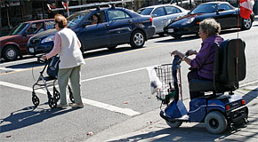 Senior women using a walker and motorized scooter using a crosswalk