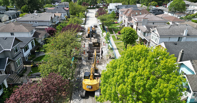 Aerial view of sewer upgrade construction on a residential street in the Shaughnessy area, with excavators, crews, and open trenches surrounded by houses and trees. Aerial view of sewer upgrade construction on a residential street in the Shaughnessy area, with excavators, crews, and open trenches surrounded by houses and trees.
