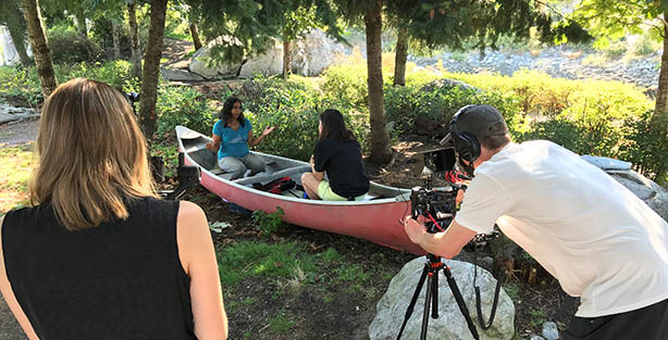 Person filming people in a canoe on grass