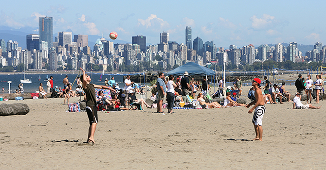 Beach goers at Spanish Banks beach play volleyball