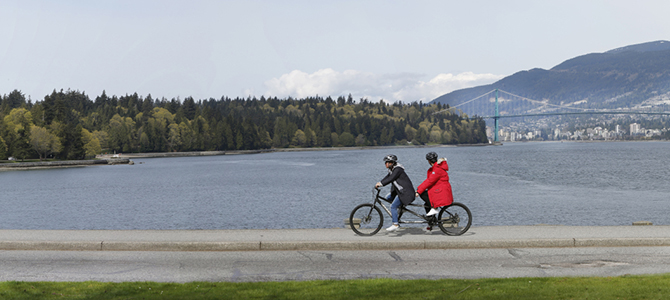 Cyclists on the Stanley Park Seawall with Lion's Gate Bridge in the background 