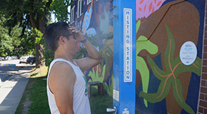 Person standing in front of a misting station spreading some of the water on their forehead
