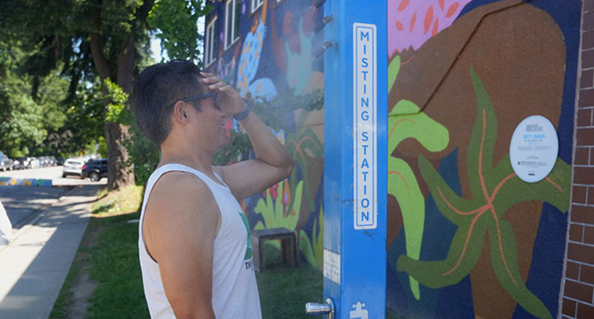 Person standing in front of a misting station spreading some of the water on their forehead