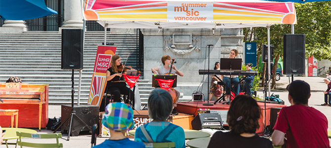 Outdoor summer concert with a band playing under an event tent with a small audience watching