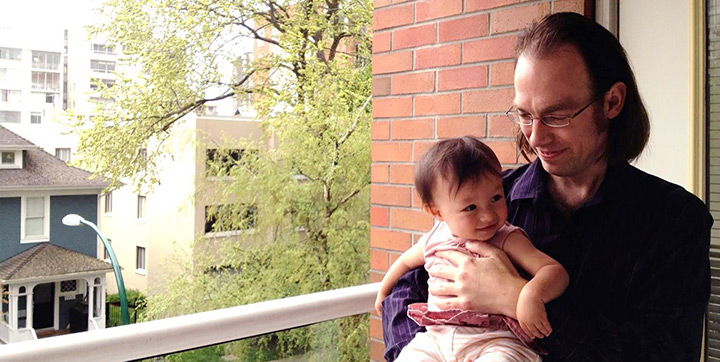 Father holding their baby on an apartment balcony in Vancouver Father holding their baby on an apartment balcony in Vancouver