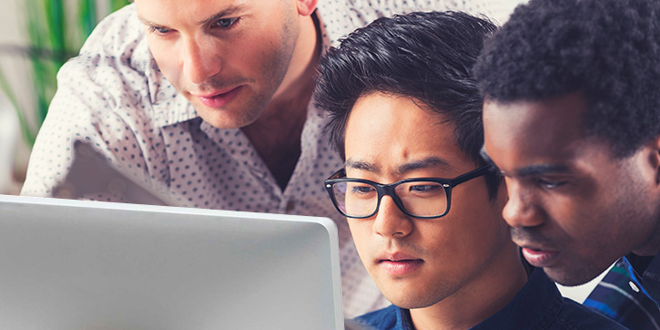 Three men look at a computer at their digital start-up business in the Technology and Social Innovation Lab.