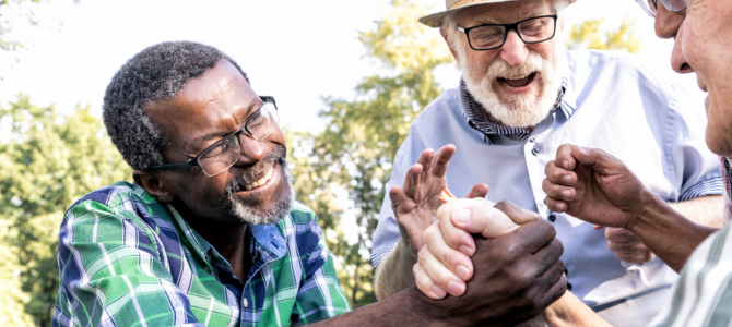 Three seniors laughing together and holding hands