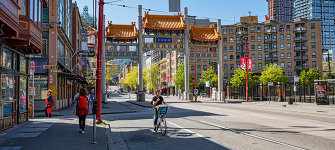 A person biking in front of the gates in Vancouver's Chinatown