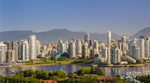 Skyline of downtown Vancouver on a clear summer day, with high-rise buildings in the foreground, sailboats in False Creek, and the North Shore Mountains in the background.