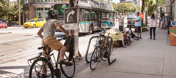 Cyclist getting off their bike on a Vancouver sidewalk