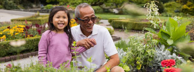 Older man and young girl smiling in a garden