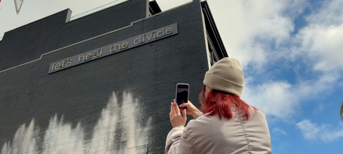 A women takes a photo of a wall with the words 