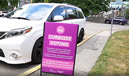 Vehicle parked in front of curbside voting sign