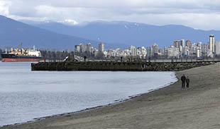 People walking on the beach with skyline and mountains in the background