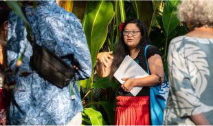 A person leading a discussion inside the Bloedel Conservatory, with visitors in the foreground.