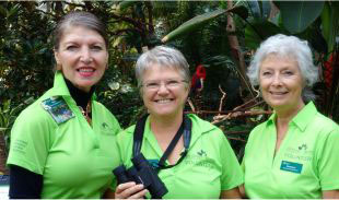 Volunteers wearing green shirts posing inside the Bloedel Conservatory’s tropical garden.
