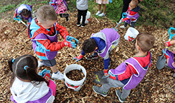 Children gathering mulch and putting it in a bucket