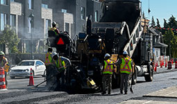 A truck constructions workers placing ashphalt onto the road