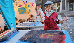 A woman uses a bottle of dish soap to create a art at a street craft fair event.