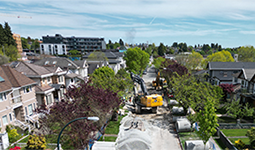 Construction crews and equipment working on East 35th Avenue to upgrade sewer infrastructure in a residential neighbourhood.