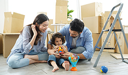 A family sitting on a floor with moving in equipment 