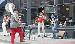 Musicians playing instruments on Water St outside of a restaurant in Gastown