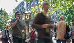 A busy street full of pedestrians walking near the steam clock in Gastown