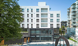 Front view of the completed Little Mountain building with ground-floor storefronts and apartments above