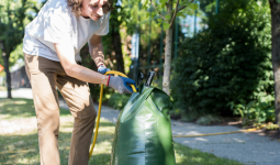 A person filling a watering bag with water outside