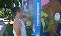 Person standing in front of a misting station spreading some of the water on their forehead