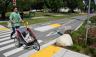 Person with stroller walking in the middle the road to a curb