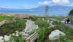 2 children walking next to a creek at Tatlow and Volunteer Park, north shore mountains visible in the background.