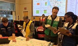 A team of City staff looking at clipboards and a map together