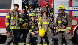 A group of firemen in front of a fire struck