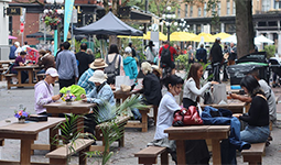 Public users sitting in a group of picnic tables set out on the street in Gastown